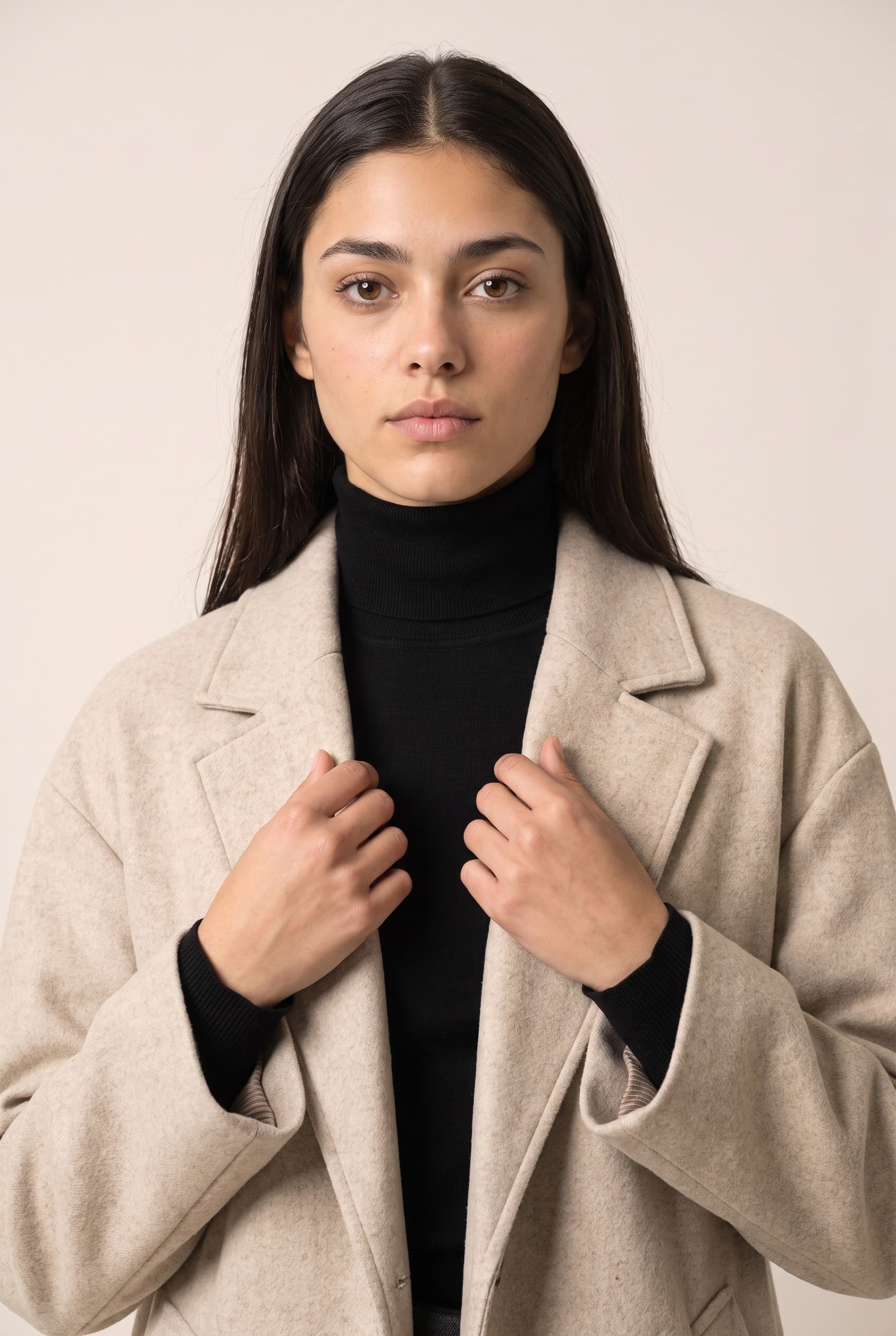 Waist-up crop of the same model with both hands adjusting the coat lapel, showing the woven wool texture and the knit at the collar
