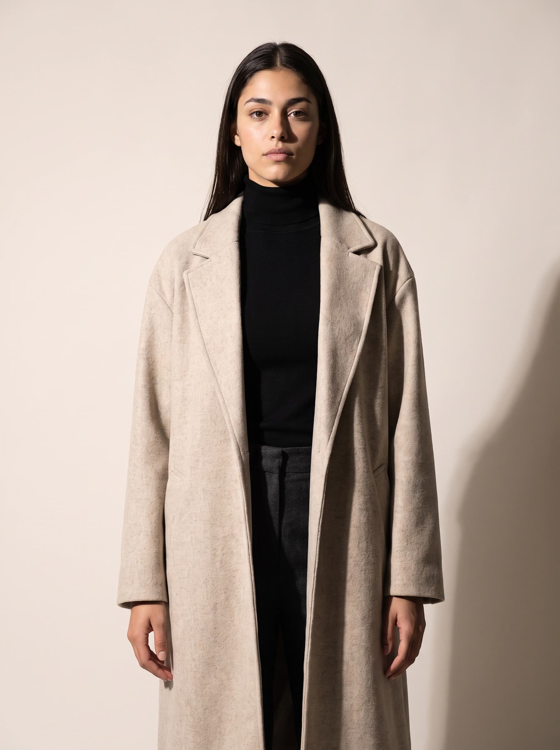 The same model and pose lit by a hard source from the left, casting a crisp shadow on the backdrop and raking texture across the wool