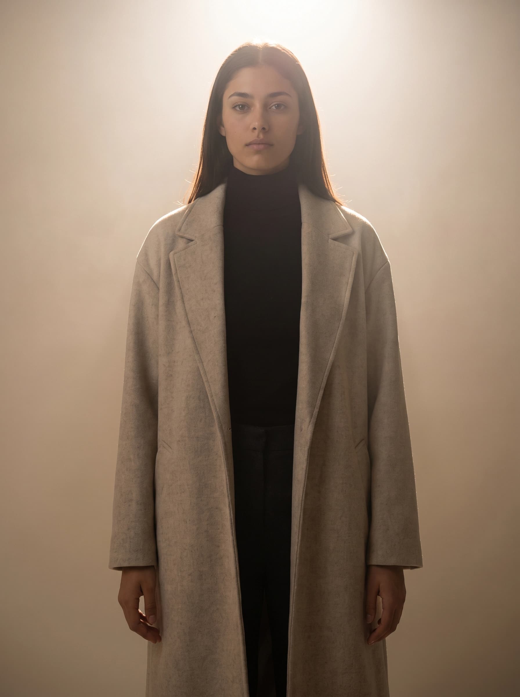 The same model and pose lit from high behind, with a bright halo on her hair and shoulders and her face in soft shade
